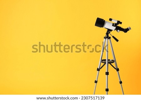 Tripod with modern telescope on yellow background. Space for text