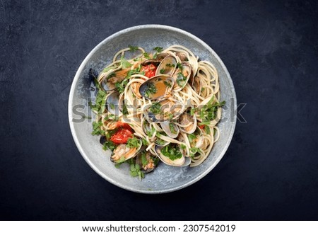 Spaghetti alle vongole with tomato in seafood jus served as top view at a Nordic design bowl with copy space