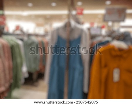Defocused Abstract Background of female clothes store hanging on rack in departement store inside modern Shopping Mall or Shopping Center. 
