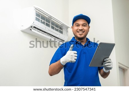 Technician in uniform using tablet to check list of maintenance and cleaning filters of air conditioner. Air condition maintenance service. Home services concept. Royalty-Free Stock Photo #2307547341