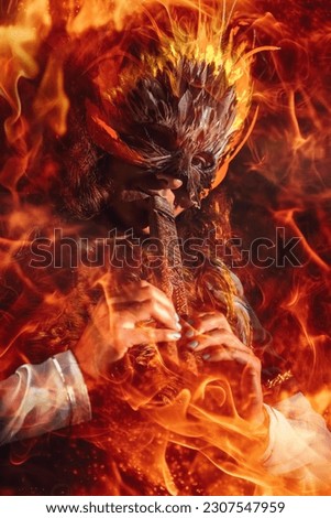 girl with shamanic feather mask playing on wooden ornamental flute. Fire effect.