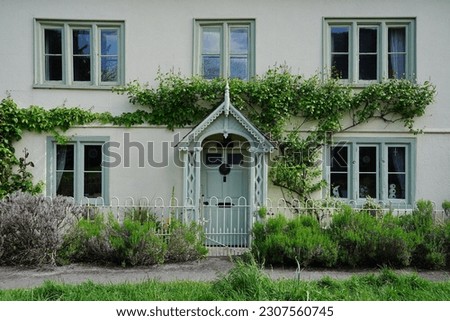 Exterior view, wooden front door and leafy garden of a beautiful old town house on a street in an English city Royalty-Free Stock Photo #2307560745