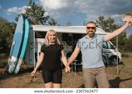 A happy loving couple Is resting near their motorhome in nature.
