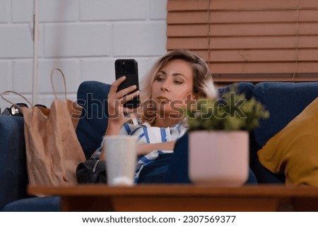 Young woman watch movies on mobile phone, using network internet online, and entertainment application at home. Shopping online by searching websites to find products. Gadget device technology