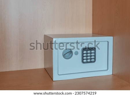 A small metal safe inside a cabinet with password buttons to store valuables. The concept is the purchase of a cash box. Royalty-Free Stock Photo #2307574219