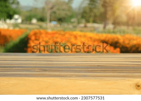 Empty wooden surface against bright sunshine flower field in springtime blur background , display podium for product mockups 3d trade show display advertising, For text and advertising.