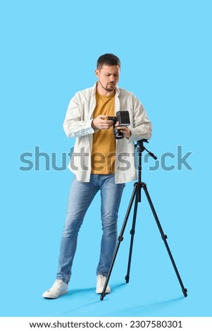 Upset male photographer with professional camera on blue background