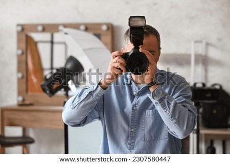 Mature photographer with professional camera in studio