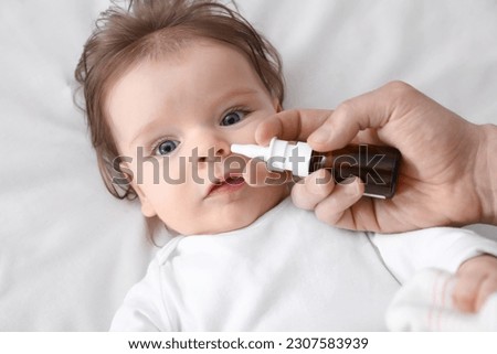 Father taking care of little baby suffering from runny nose in bed, top view Royalty-Free Stock Photo #2307583939