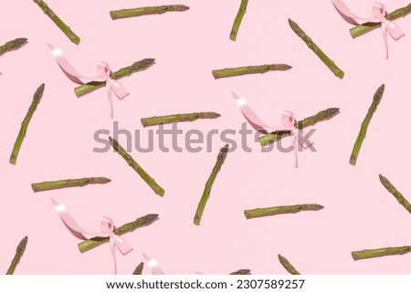 Fresh asparagus, creative food pattern, pastel pink background. 