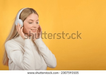 cute young blonde woman enjoying music in headphones