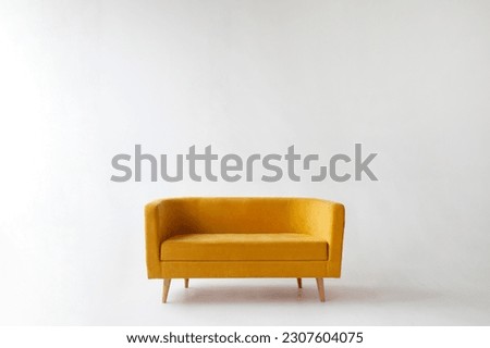 soft empty yellow sofa stands on white isolated background, comfortable fabric couch is alone against the background of white wall, copy space Royalty-Free Stock Photo #2307604075