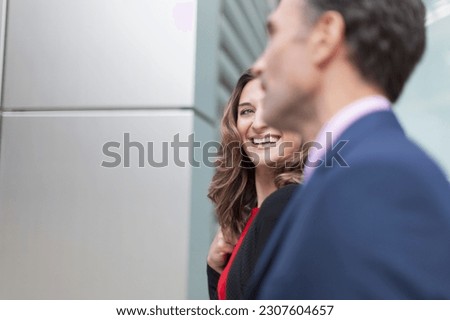 Corporate businesswoman smiling at businessman