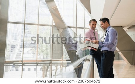 Corporate businessmen discussing paperwork in modern lobby
