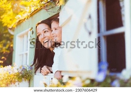 Smiling mother and daughter in playhouse window Royalty-Free Stock Photo #2307606429