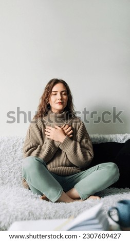 Beautiful young woman in lotus pose on bed practicing pranayama breathing techniques, finding inner balance after a stressful day Royalty-Free Stock Photo #2307609427