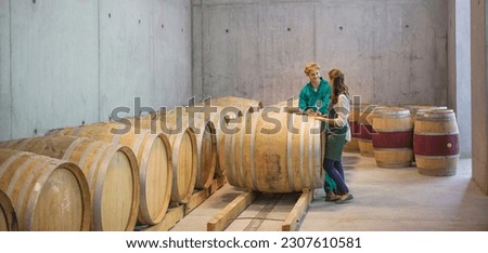 Vintners talking at barrels in winery cellar Royalty-Free Stock Photo #2307610581