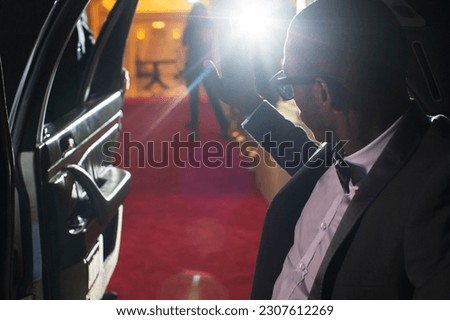 Celebrity in limousine arriving at red carpet event waving to photographing paparazzi Royalty-Free Stock Photo #2307612269