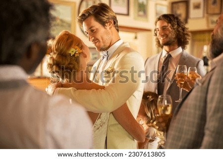 Bridegroom embracing bride during wedding reception in domestic room