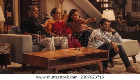 Portrait of Happy Indian Family Enjoying Movie Playing on TV at Home Together. Parents and Young Adult Children Share Love for Cinema, watching Favourite Streaming Service TV Shows. Royalty-Free Stock Photo #2307623715