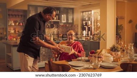 Surprise Gift: Loving Elderly Indian Husband Presents a Gift to the Wife, Love of His life. Gorgeous Woman Happy in Marriage Receives Birthday Present, He Hugs Her Tenderly.