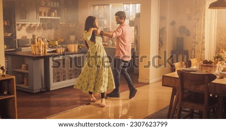 Young Couple Dancing and Having Fun in the Kitchen: Enjoying Each Other's Company and Playfully Moving to Music. With Joyful Laughter and Smiles, they Embrace the Music and Dance Royalty-Free Stock Photo #2307623799