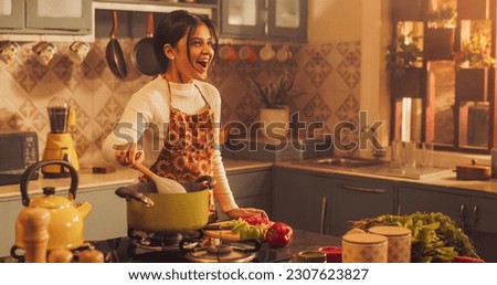 Indian Girl Preparing Food: Magnificent Young Woman Smiling Happily as She Gets Surprised by Family and Friends Visting While Preparing Delicious Home-Cooked Traditional Meal in Cosy Kitchen Royalty-Free Stock Photo #2307623827