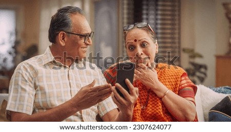 Amazing Elderly Indian Couple Using Smartphone for Video Call at Home. Beautiful Hindu Granparents Waving and Greeting Grandchildren, Talking with Relatives and Friends. Medium Close-up Royalty-Free Stock Photo #2307624077