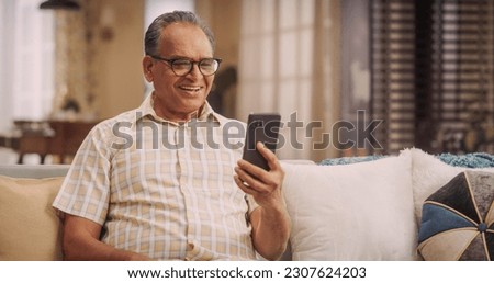 Elderly Indian Man Using Phone for Video Call, Smiling and Happy: Talking with Old Friends and Sharing Life Updates. Cherishing Meaningful Conversations and Laughter with Family Remotely Royalty-Free Stock Photo #2307624203