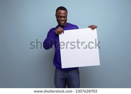 30s dark-skinned American man dressed in a blue sweater shows a white board with a mock-up