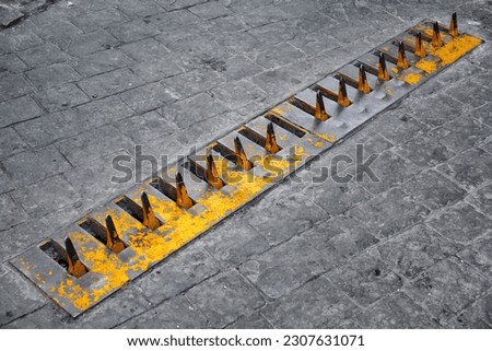 Close-up of yellow spikes for a tire puncture for stopping the car in a street of Istanbul Royalty-Free Stock Photo #2307631071