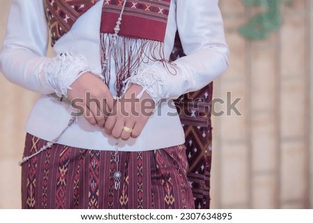 Close-up shot of bride's hands folded in front of her on wedding dress. Thai wedding dress
