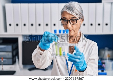 Middle age grey-haired woman scientist holding test tubes at laboratory Royalty-Free Stock Photo #2307659567