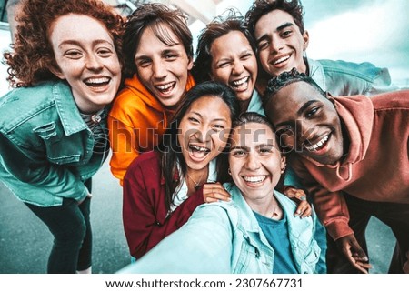 Multicultural best friends taking selfie pic with smart mobile phone outside - Laughing teenagers having fun on city street - Life style concept with guys and girls hanging out together 