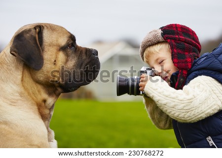 Little boy with camera is shooting his dog