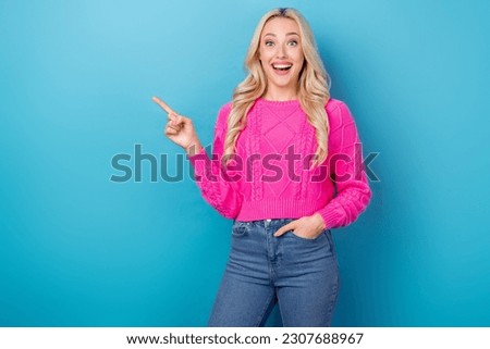 Photo of adorable excited lady wear pink sweater open mouth pointing finger empty space isolated blue color background