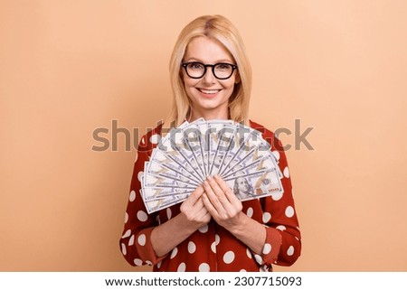 Photo of good mood cheerful satisfied woman with bob hairdo wear dotted shirt hold money got salary isolated on pastel color background