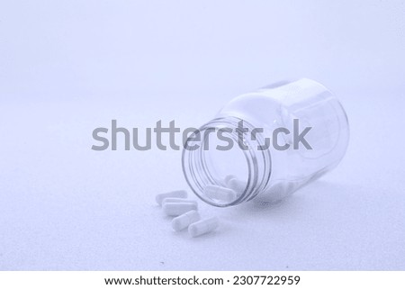 white pills in transparent plastic bottle white background