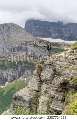 Photographer is taking a picture from Glacier NP clifftop