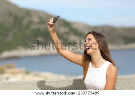Happy casual elegant girl photographing a selfie on the beach enjoying holidays and laughing