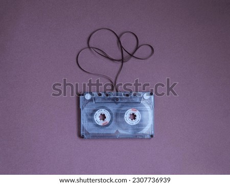 Audio cassette with tangled tape on dark purple background, top view.