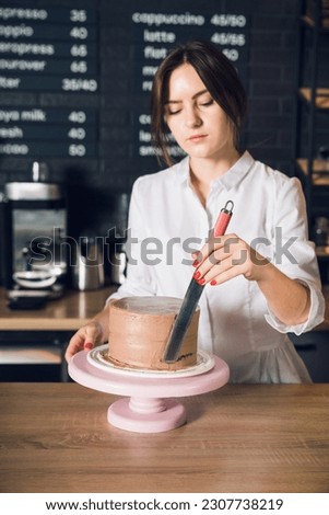 Woman's hands in white shirt smoothing cream on a side of chocolate