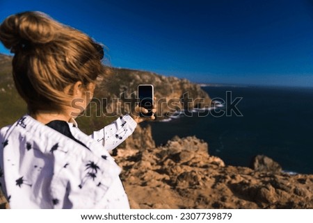 Woman taking picture of a steep cliffs on a Portuguese Landscapes