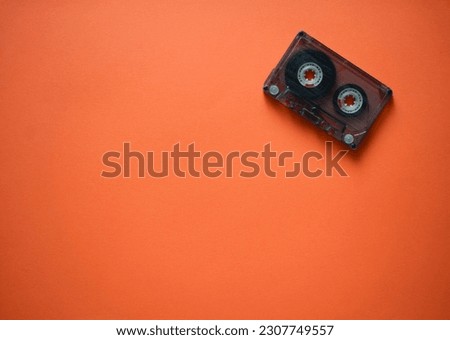 Audio cassette in the corner on an orange background, top view.