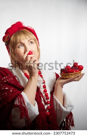 Portrait of heerful funny adult mature woman solokha with red berries. Female model in national ethnic Slavic style. Stylized Ukrainian, Belarusian or Russian woman in comic photo shoot