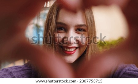 I love you. Happy young woman at home living room couch makes symbol of love, showing heart sign to camera, express romantic feelings express sincere positive feelings. Charity, gratitude, donation