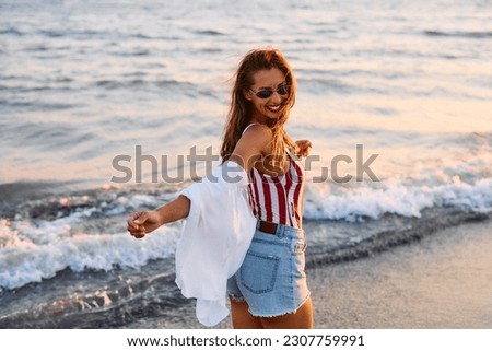 Happy woman with arms outstretched having fun on the beach. Copy space. Royalty-Free Stock Photo #2307759991