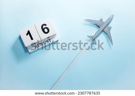August calendar with number  16. Top view of a calendar with a flying passenger plane. Scheduler. Travel concept. Copy space.