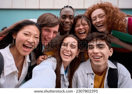 Cell phone selfie of excited multiracial group of erasmus college students together outside. Cheerful smiling young friends pose laughing for photo. Happy people on campus.
