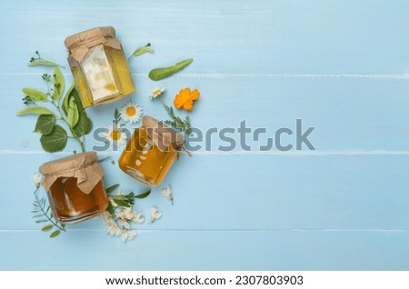 Jars with different types of honey on wooden background, top view